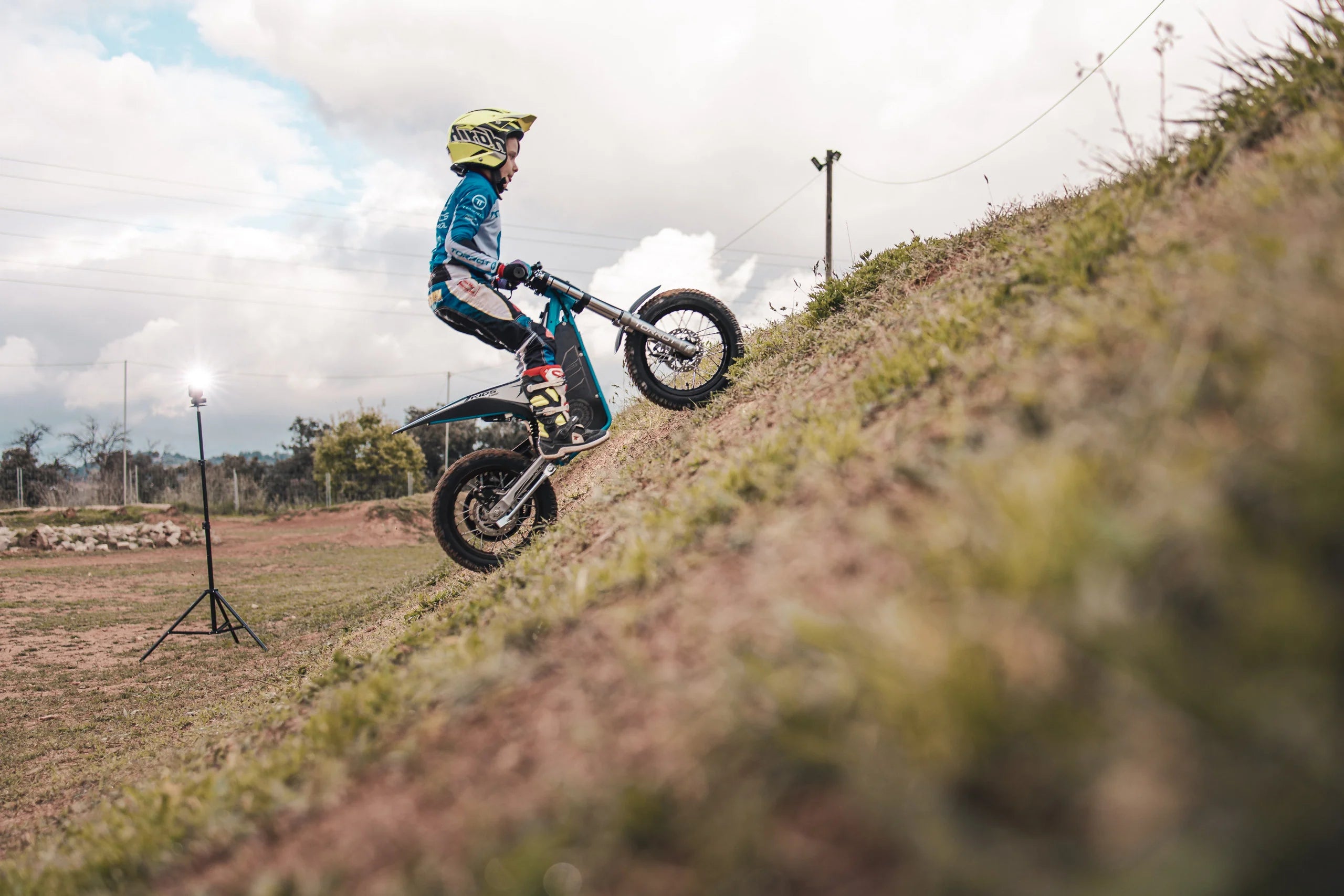 Person riding a dirt bike on a small hill with a cloudy sky in the background