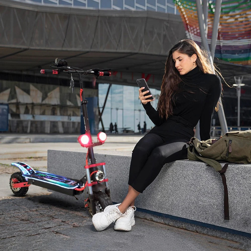 Woman sitting on a bench using a phone with an electric scooter next to her.