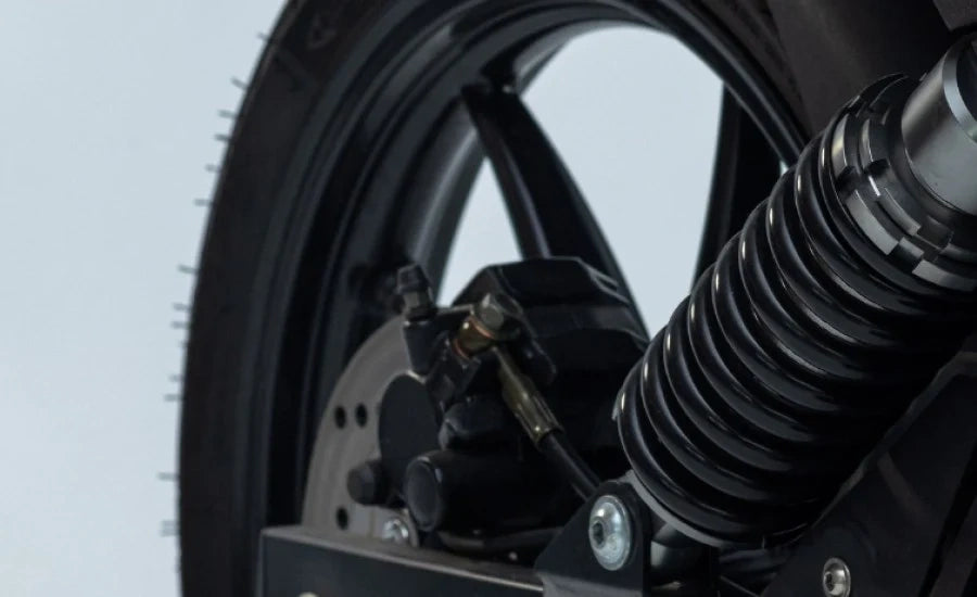 Close-up of a motorcycle wheel and suspension system on a light gray background