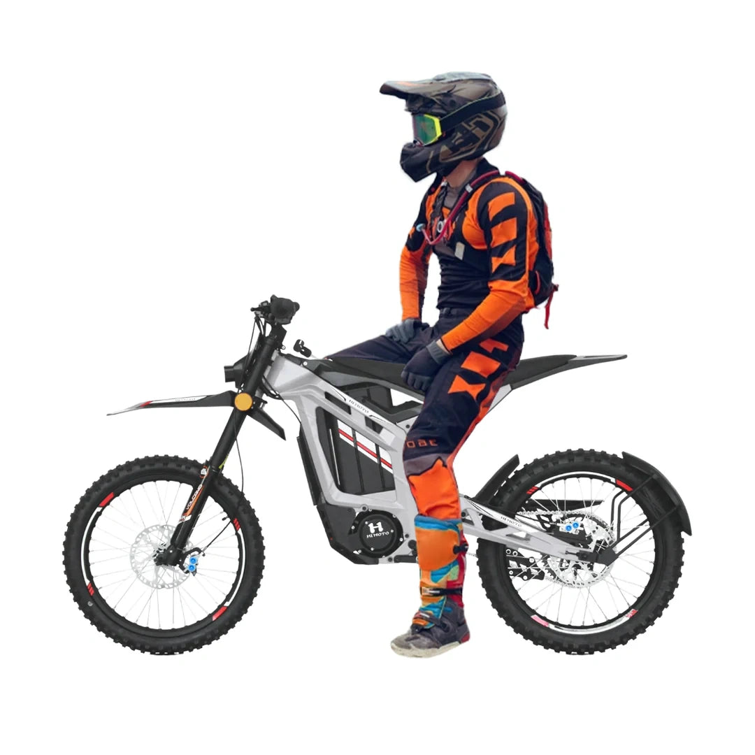 Person in motocross gear sitting on a electric bike with a white background