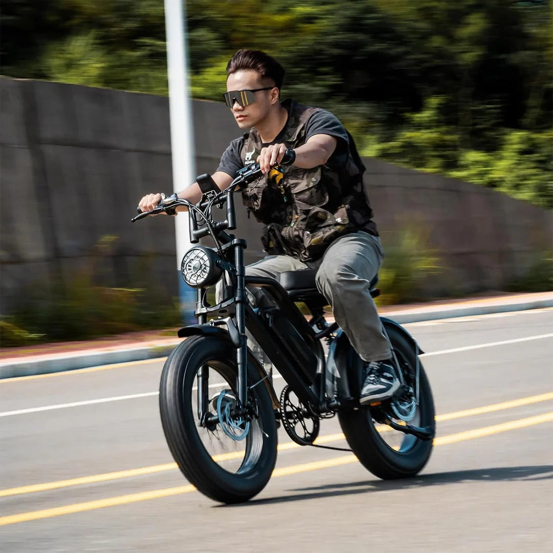 Person riding a black electric bike on a road with greenery in the background