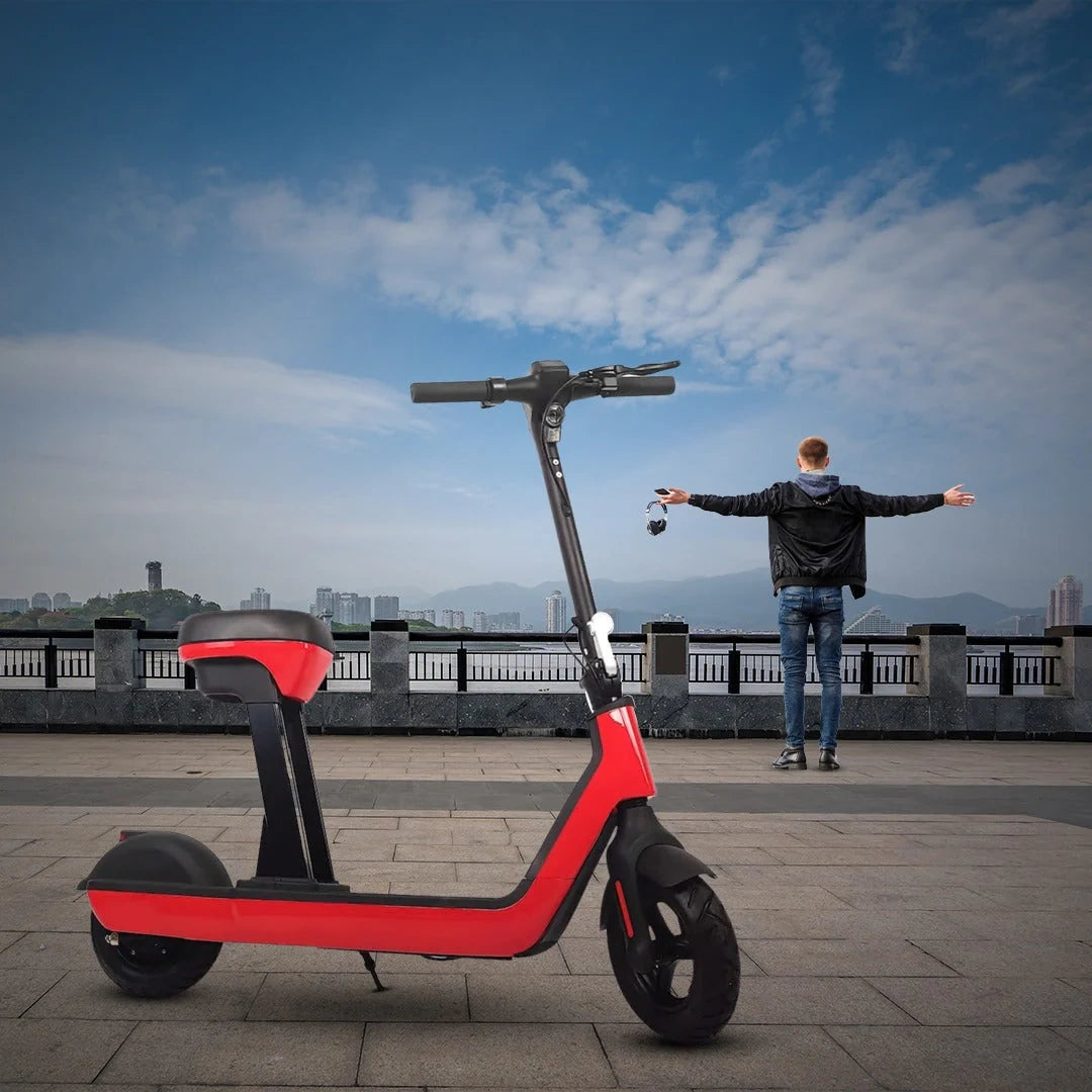 Red electric scooter on a paved area with a person standing nearby and a cityscape in the background.