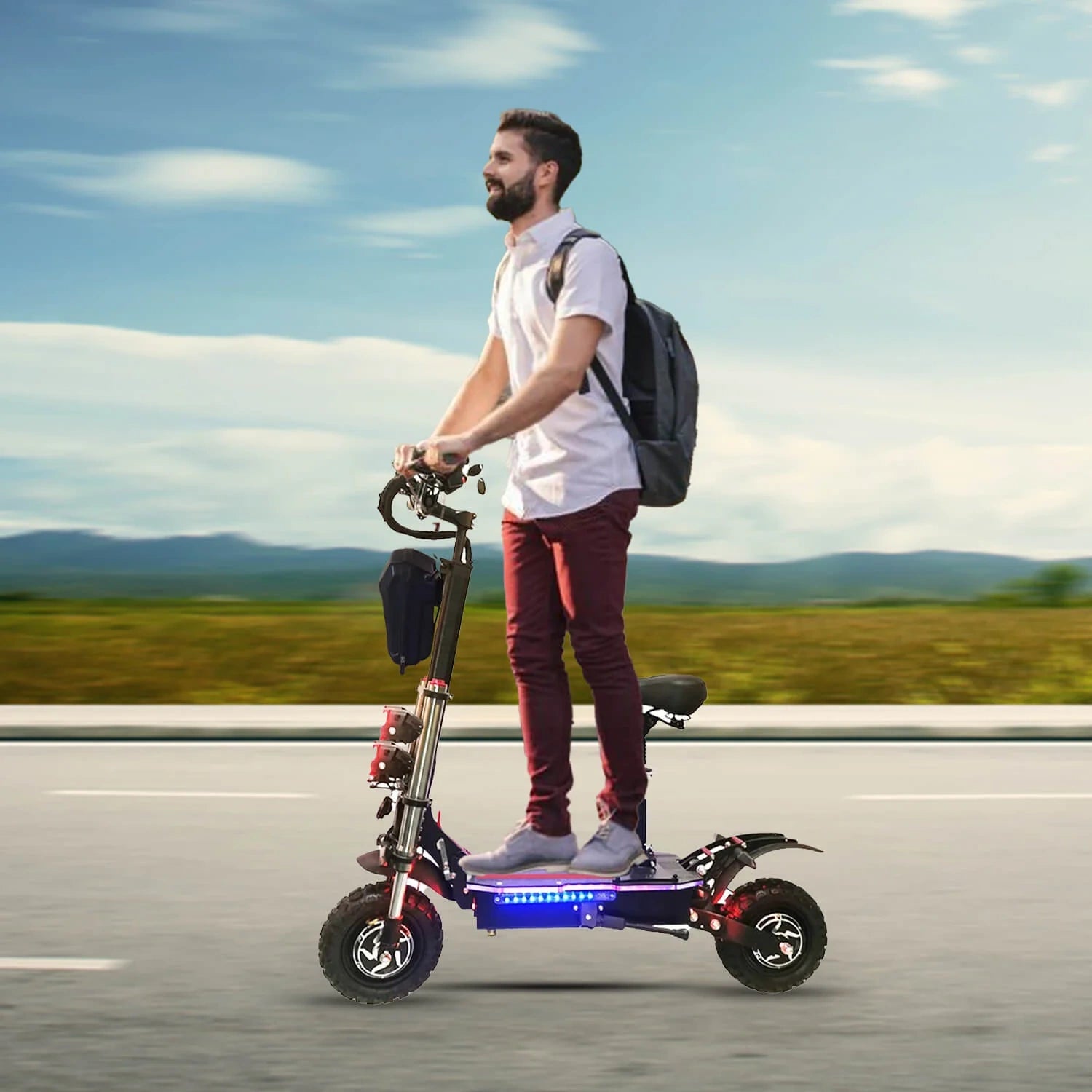 Man riding an electric scooter on a road with a clear sky and mountains in the background