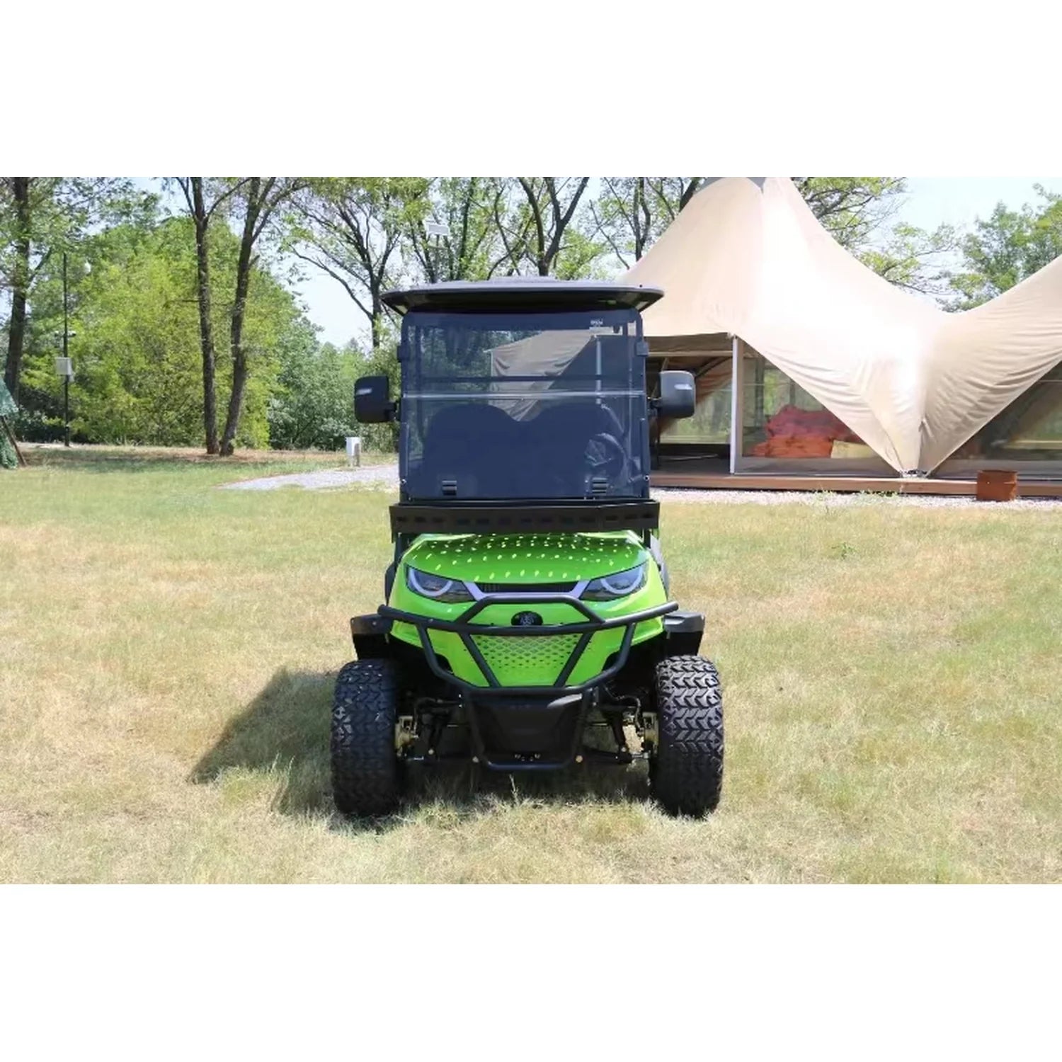 Green utility vehicle on grass with a tent in the background