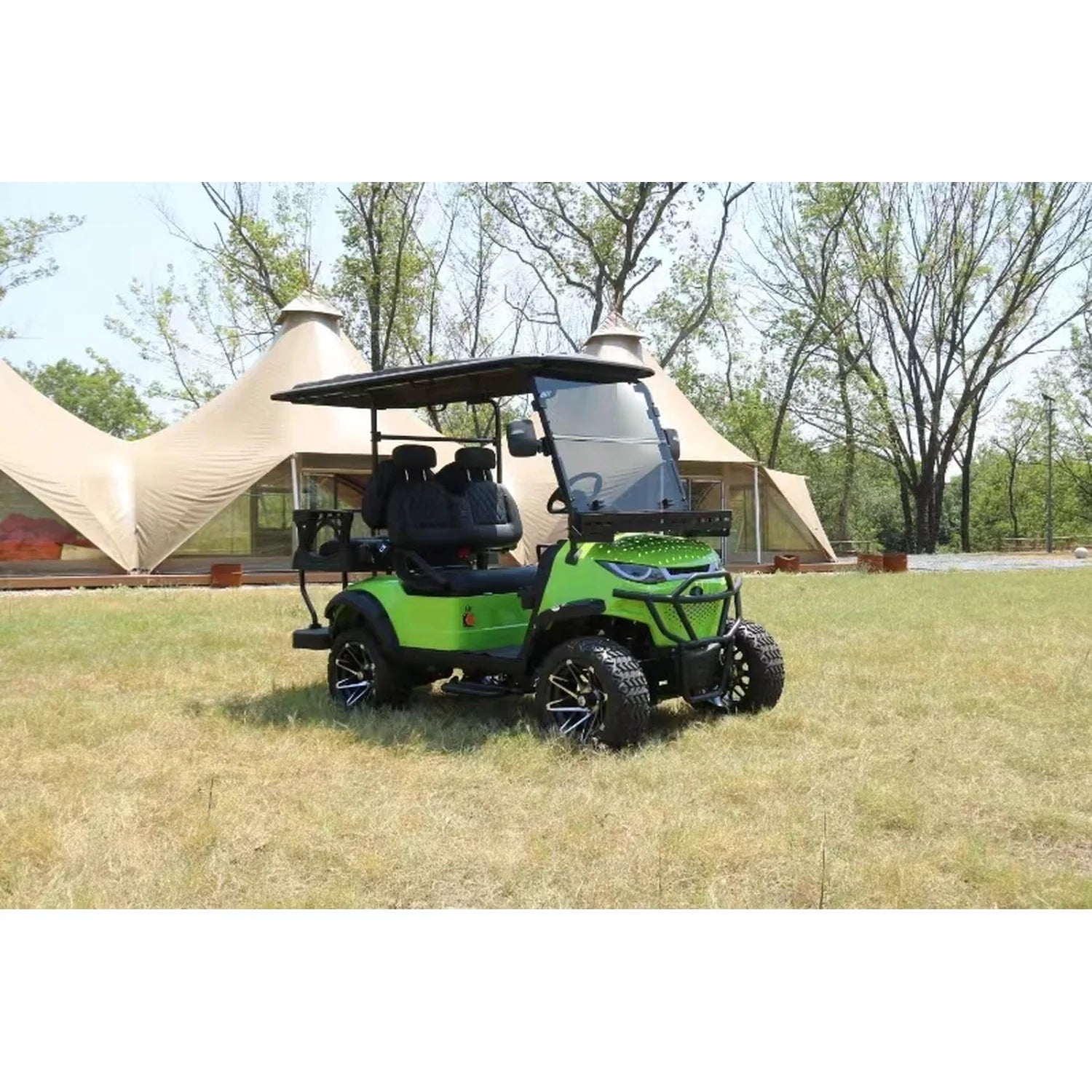 Green golf cart on grass with tents and trees in the background