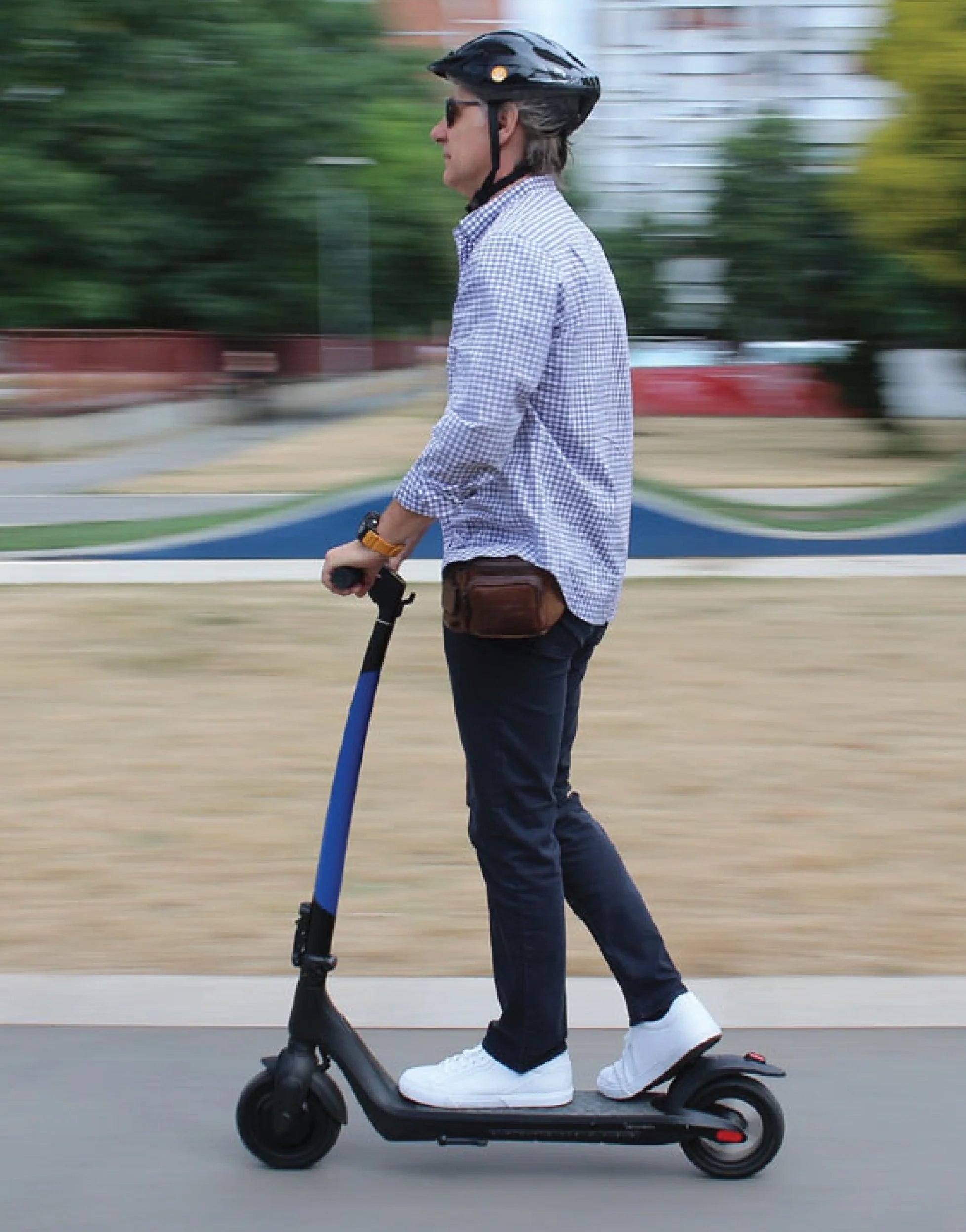 Person riding an electric scooter on a sidewalk with a blurred background