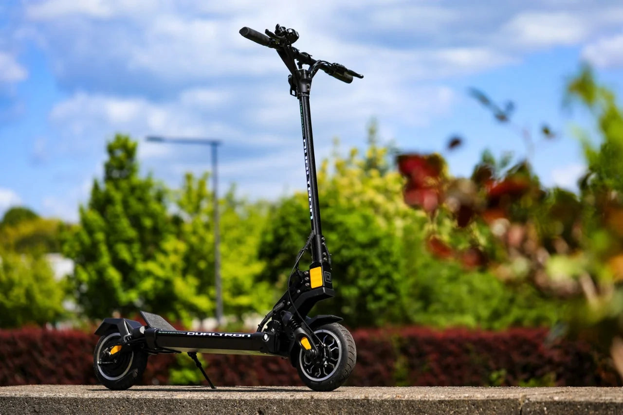 Black electric scooter on a concrete surface with a blurred natural background