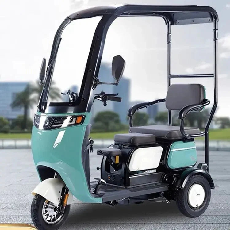 Teal three-wheeled electric vehicle with a clear canopy on a road.