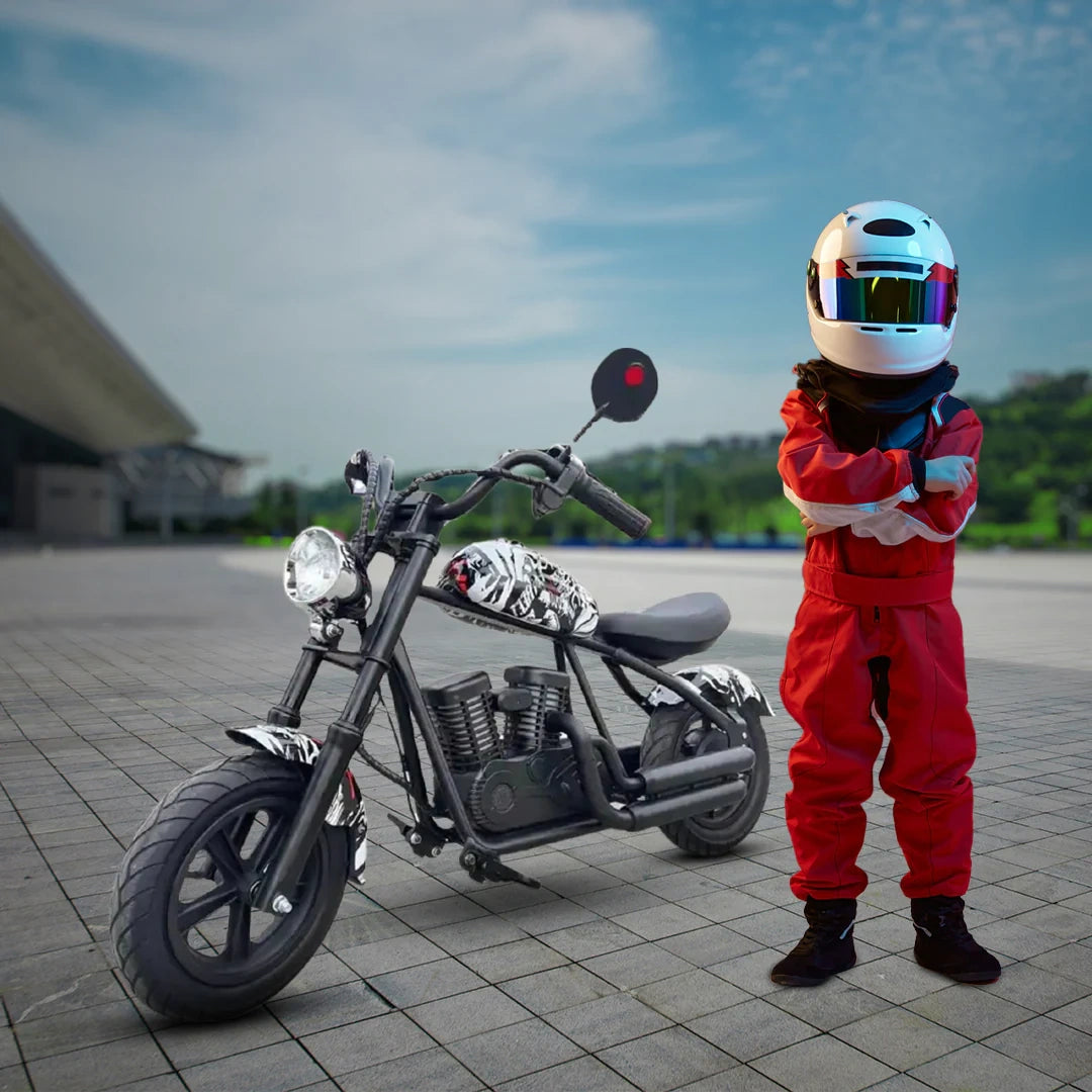 Child in red racing suit and helmet standing next to a small motorcycle on a paved area with a blurred background.