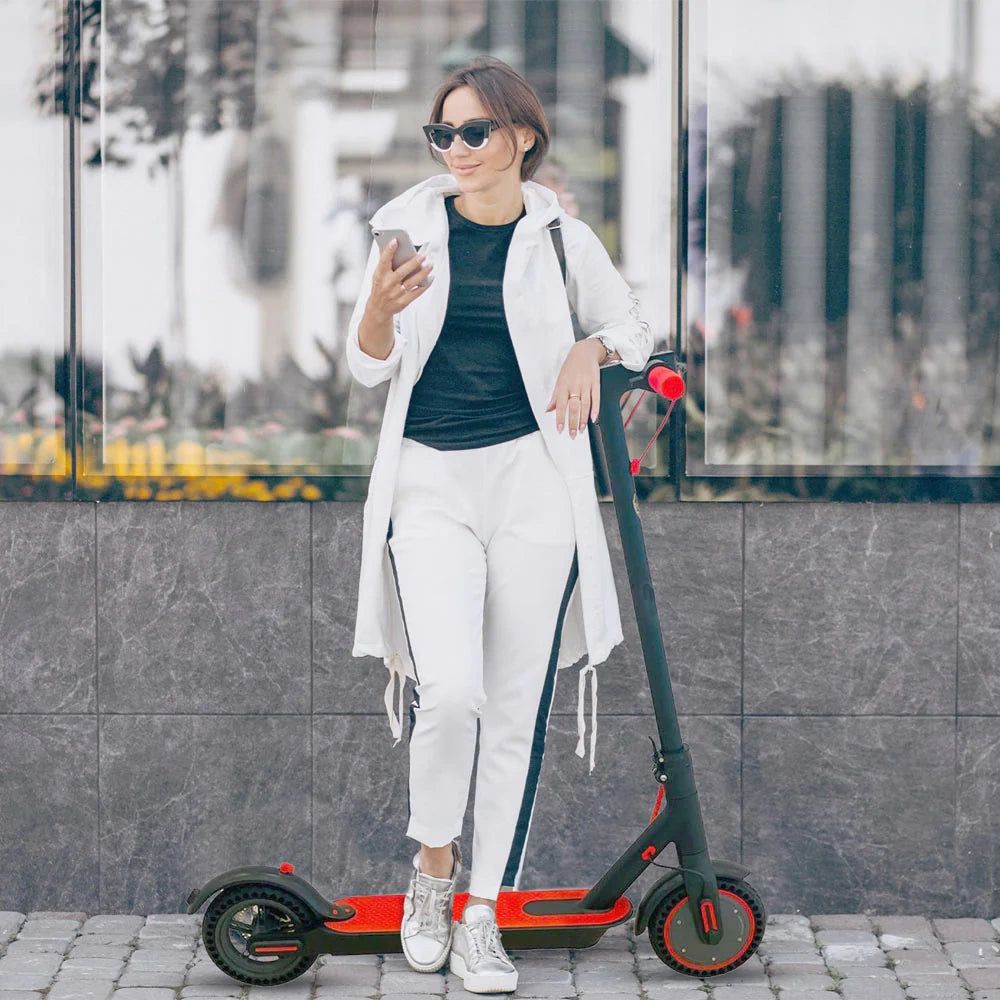 Woman standing next to an electric scooter on a city street.