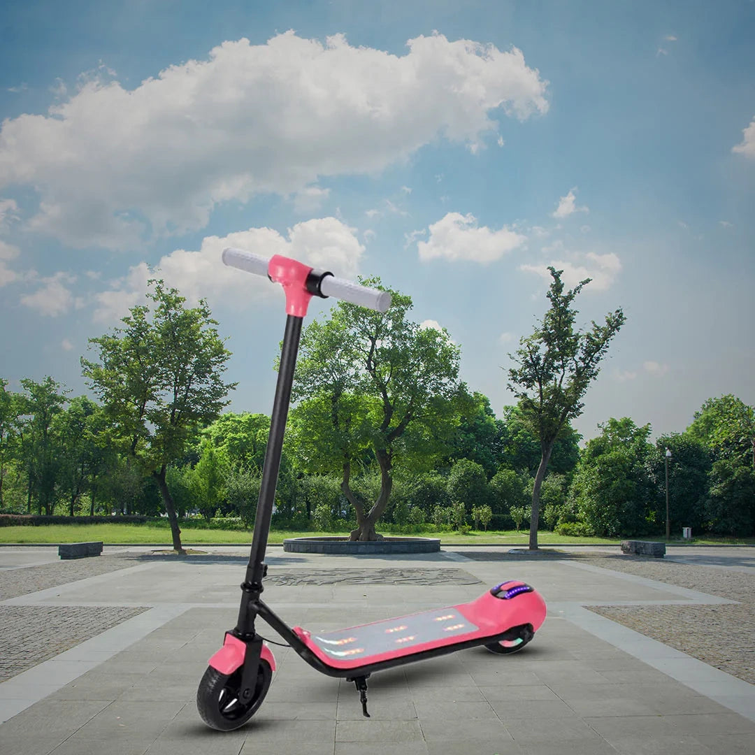 Pink electric scooter on a paved area with trees and a blue sky in the background