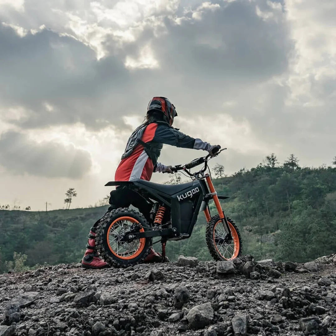 Person on a Kugoo electric bike in a mountainous landscape with cloudy sky