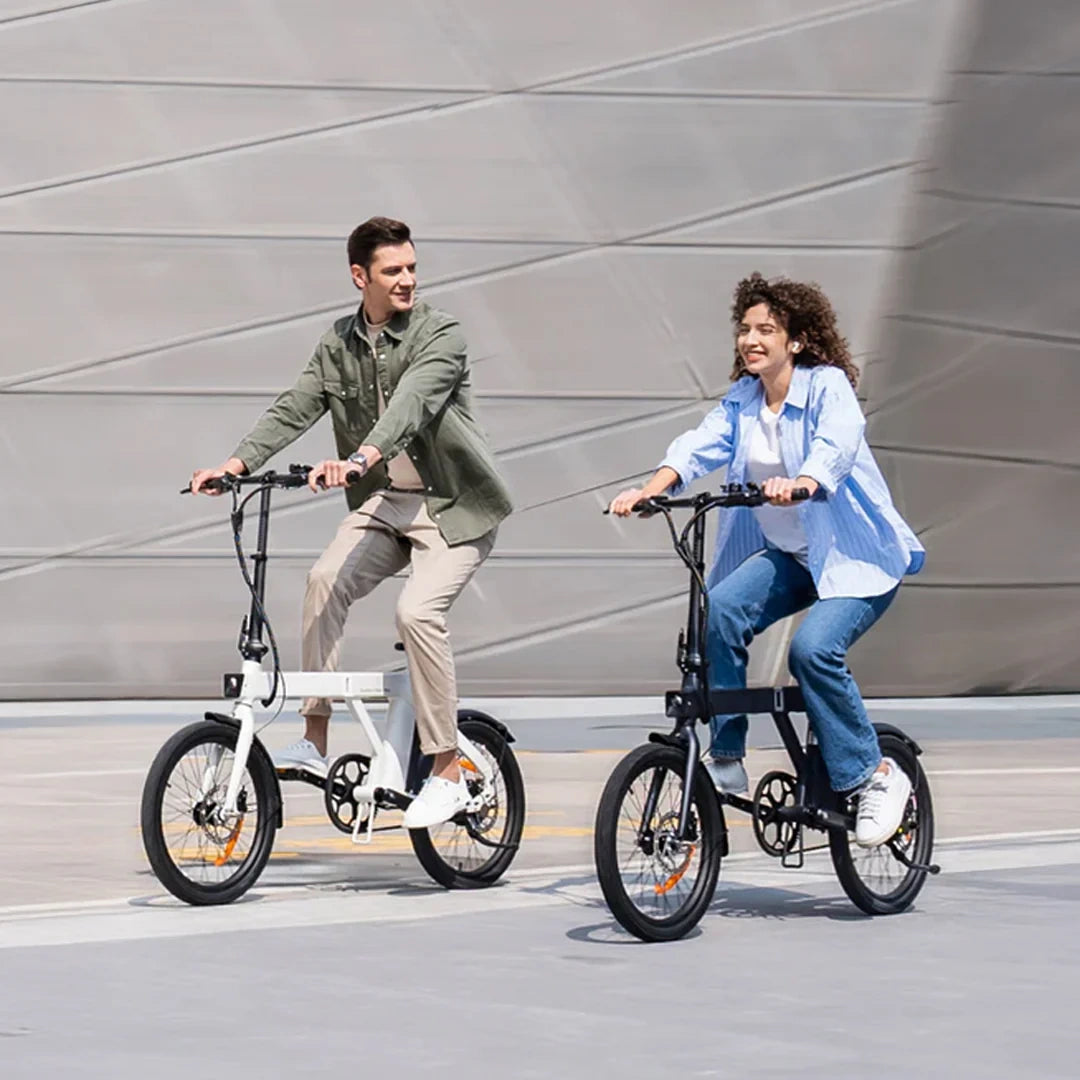 Two people riding electric bikes on a city street with a modern building in the background.