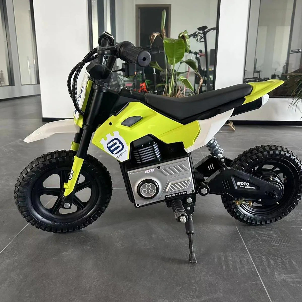 Yellow and black children's dirt bike on a gray floor with indoor background
