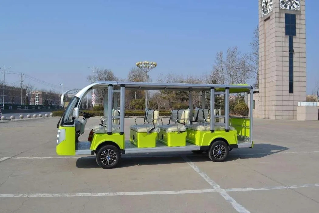 Green electric shuttle bus in a parking lot with a clock tower in the background