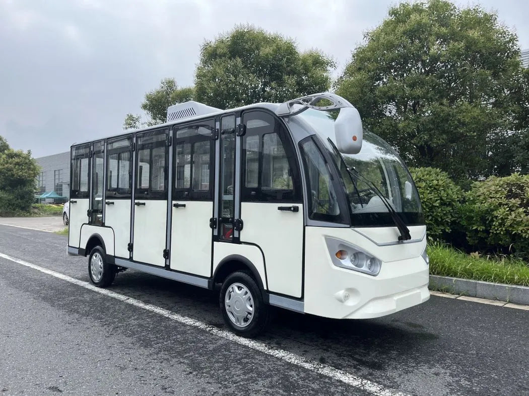 Small white bus on a road with trees in the background