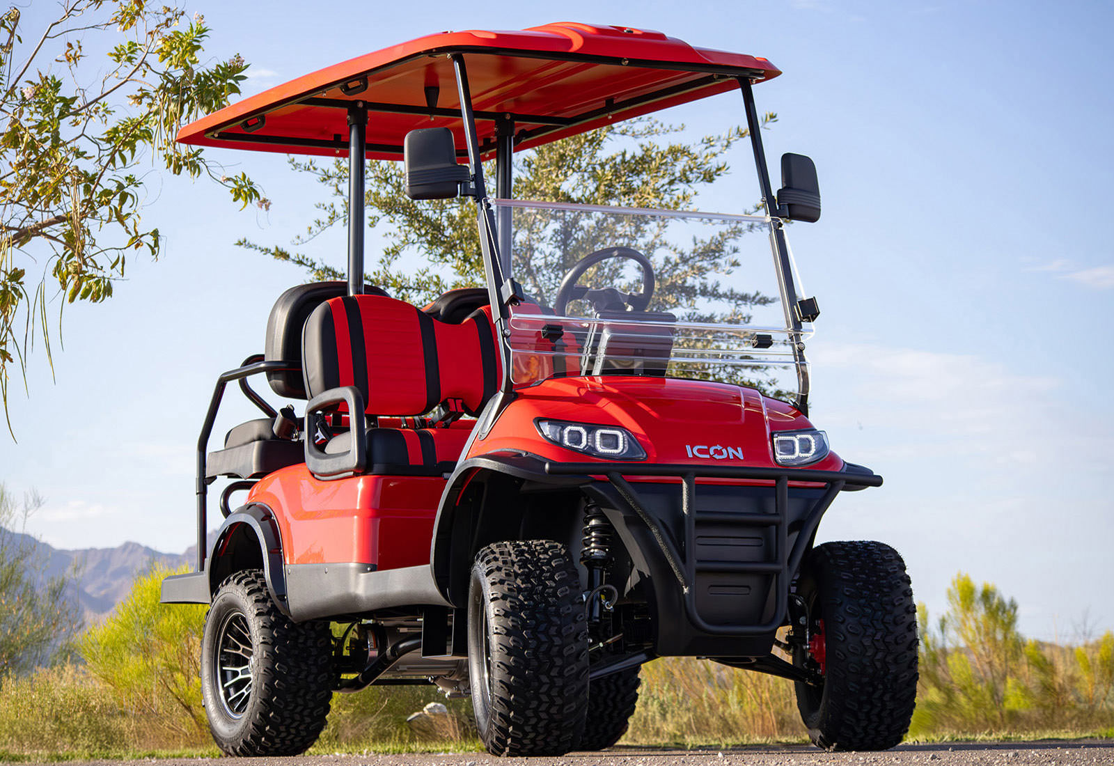 Red golf cart with 'Icon' branding on a clear day with mountains in the background