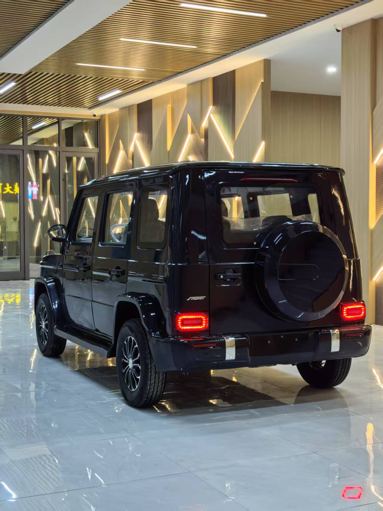 Black SUV in a showroom with reflective floor and modern interior.