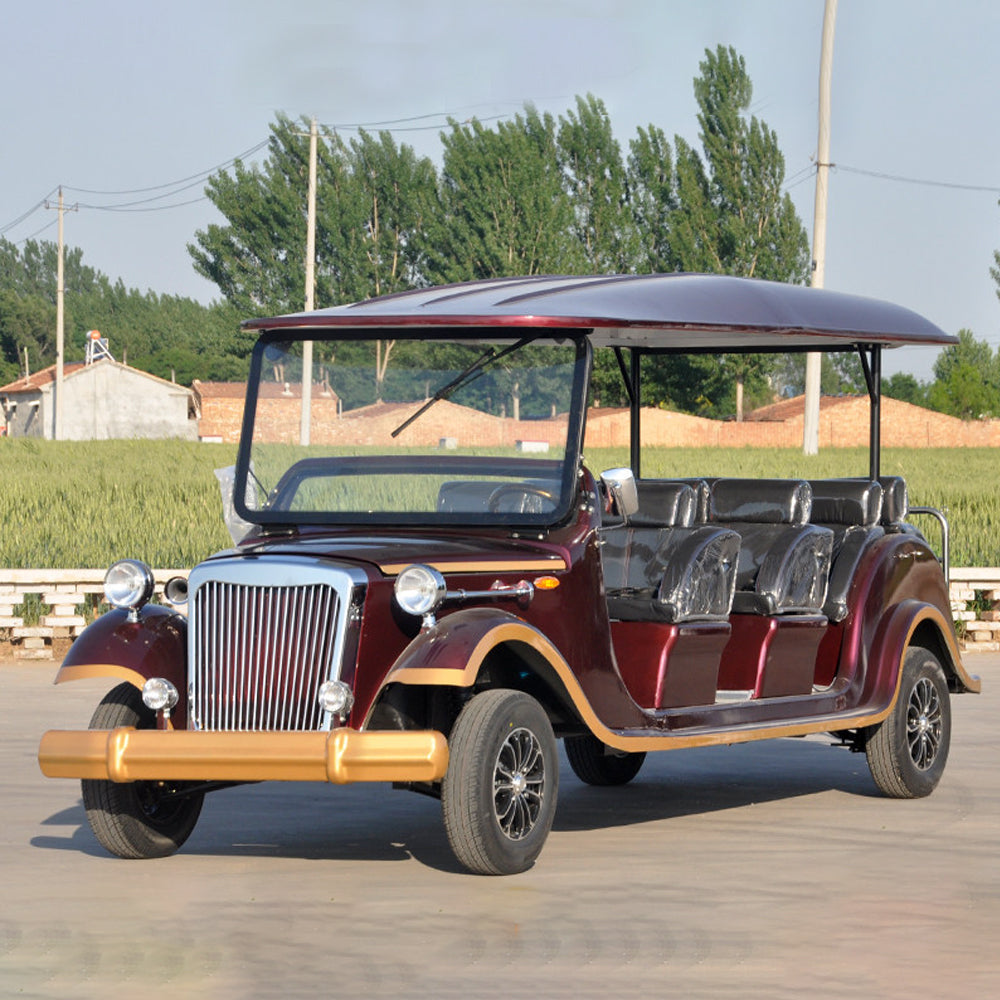 Vintage-style electric car on a road with trees and buildings in the background