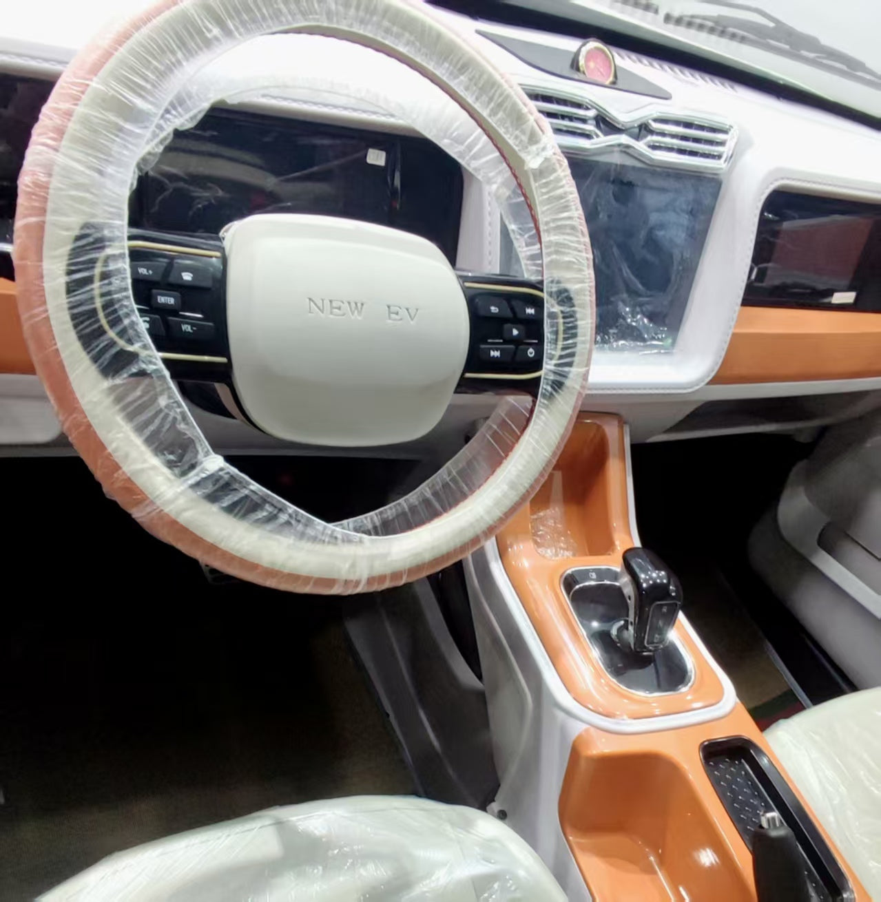 Steering wheel cover on a car steering wheel with 'NEW EV' branding.