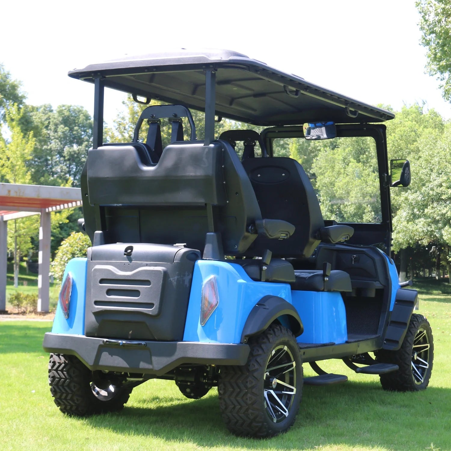 Blue and black golf cart on grass with trees in the background