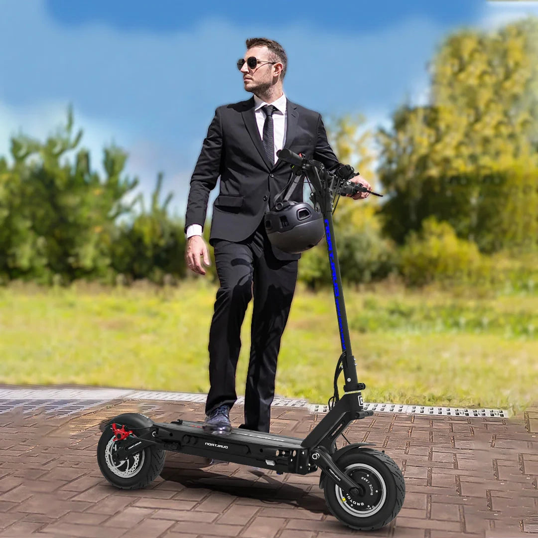 Man in a suit standing next to an electric scooter outdoors on a sunny day.