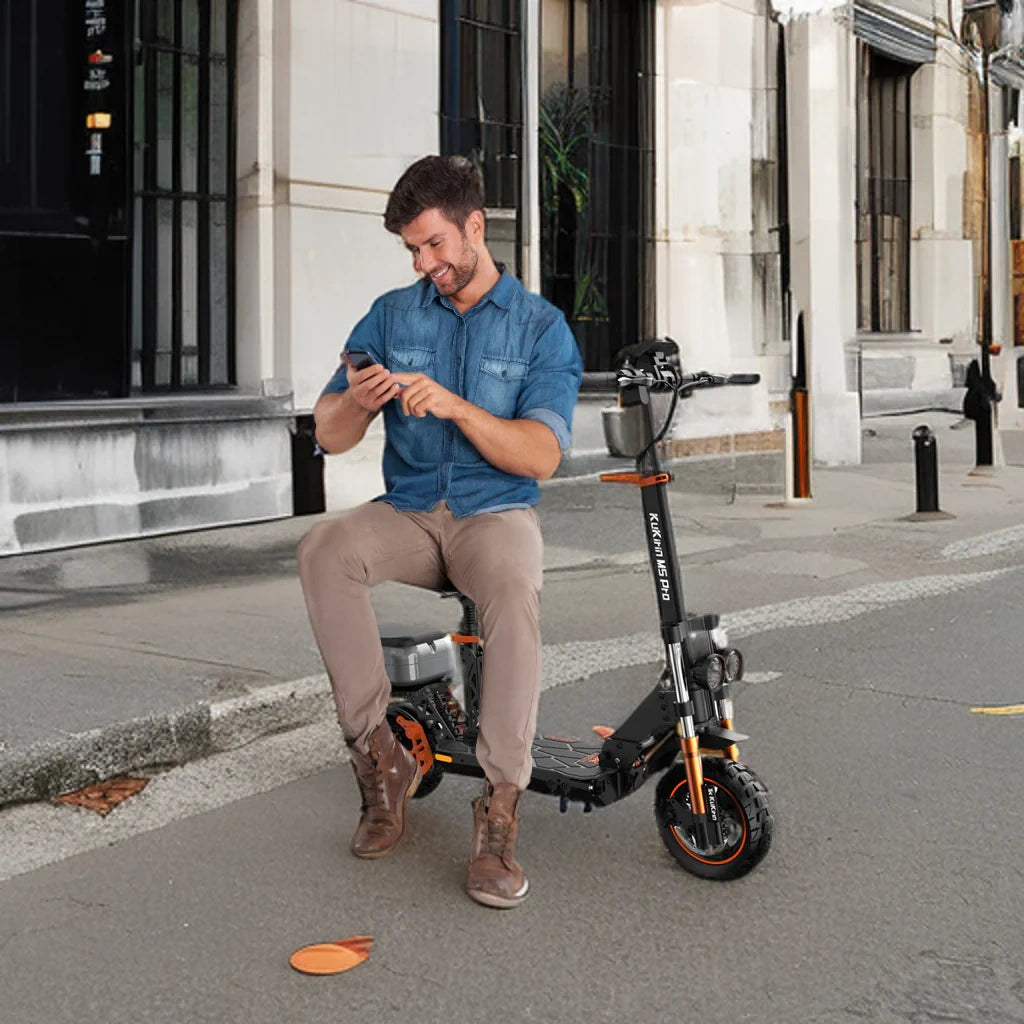 Man sitting on an electric scooter in an urban setting, using a phone.