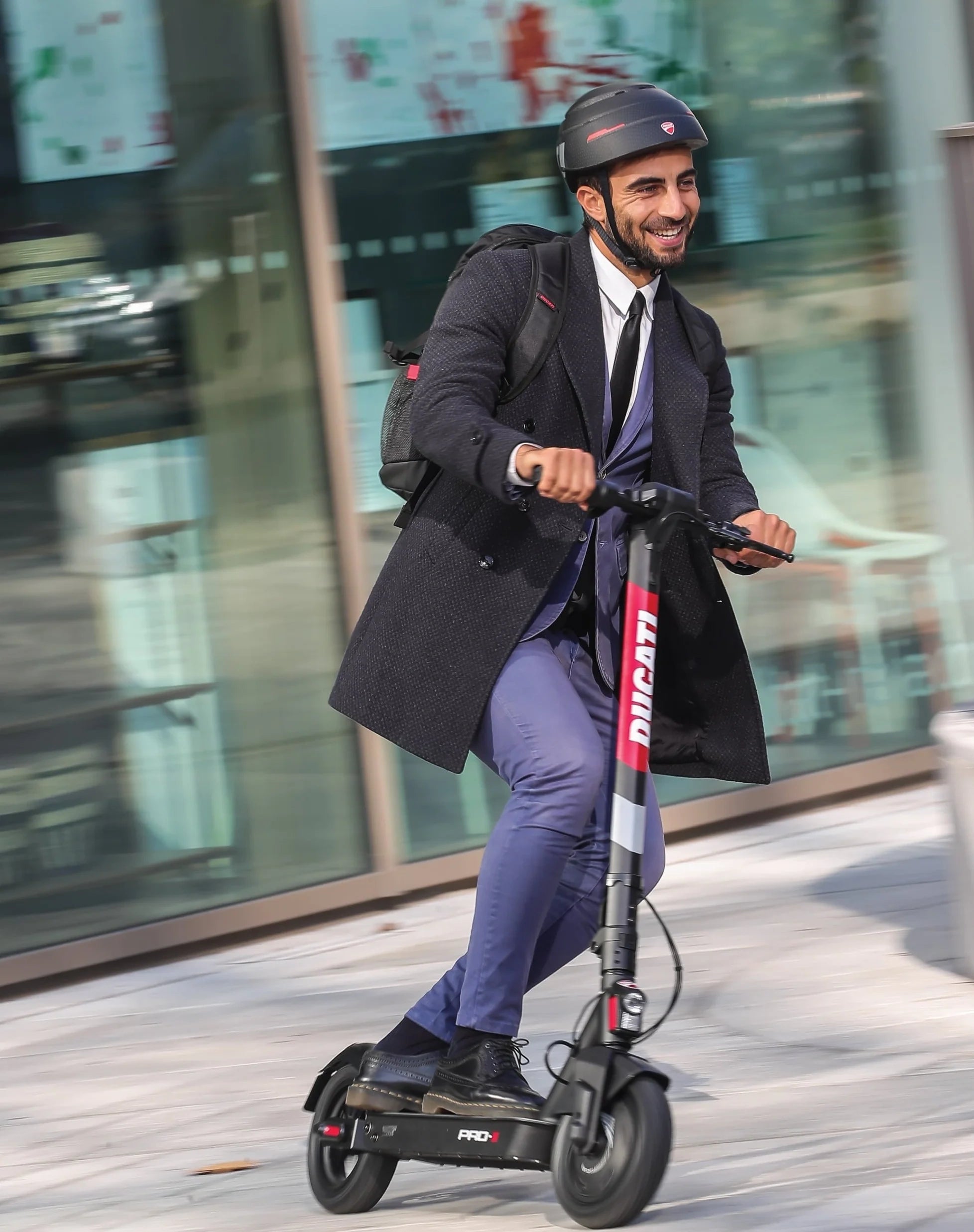 Man in a suit riding an electric scooter on a city street