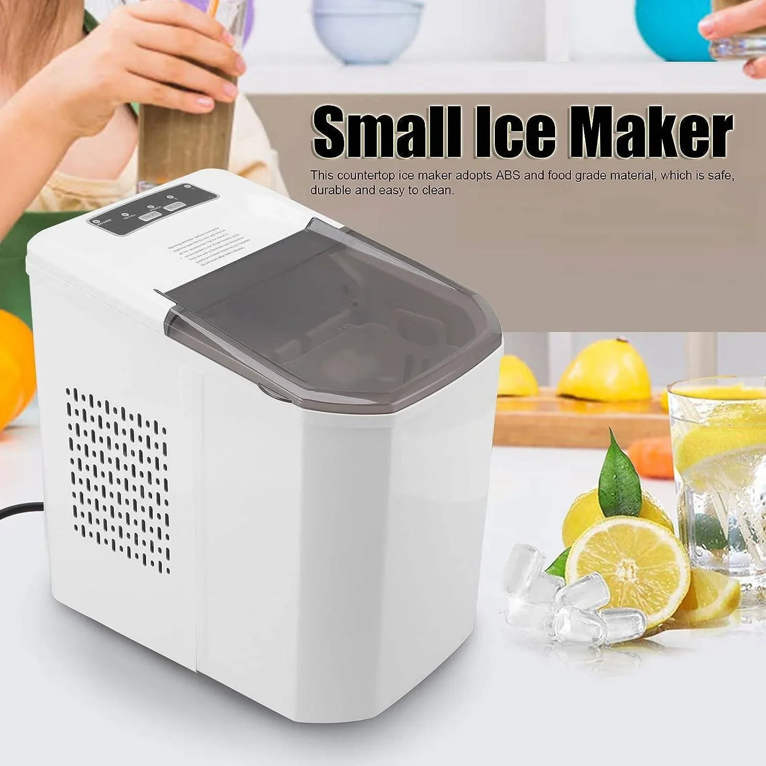 Small ice maker on a kitchen counter with lemons and a glass of water.