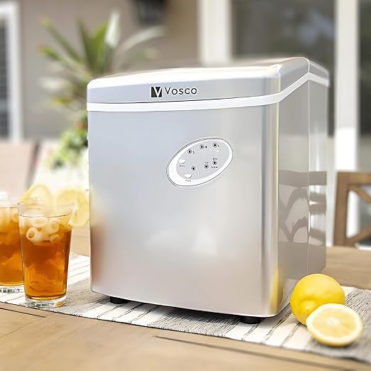 Portable ice maker on a table with lemon slices and glasses of iced tea.