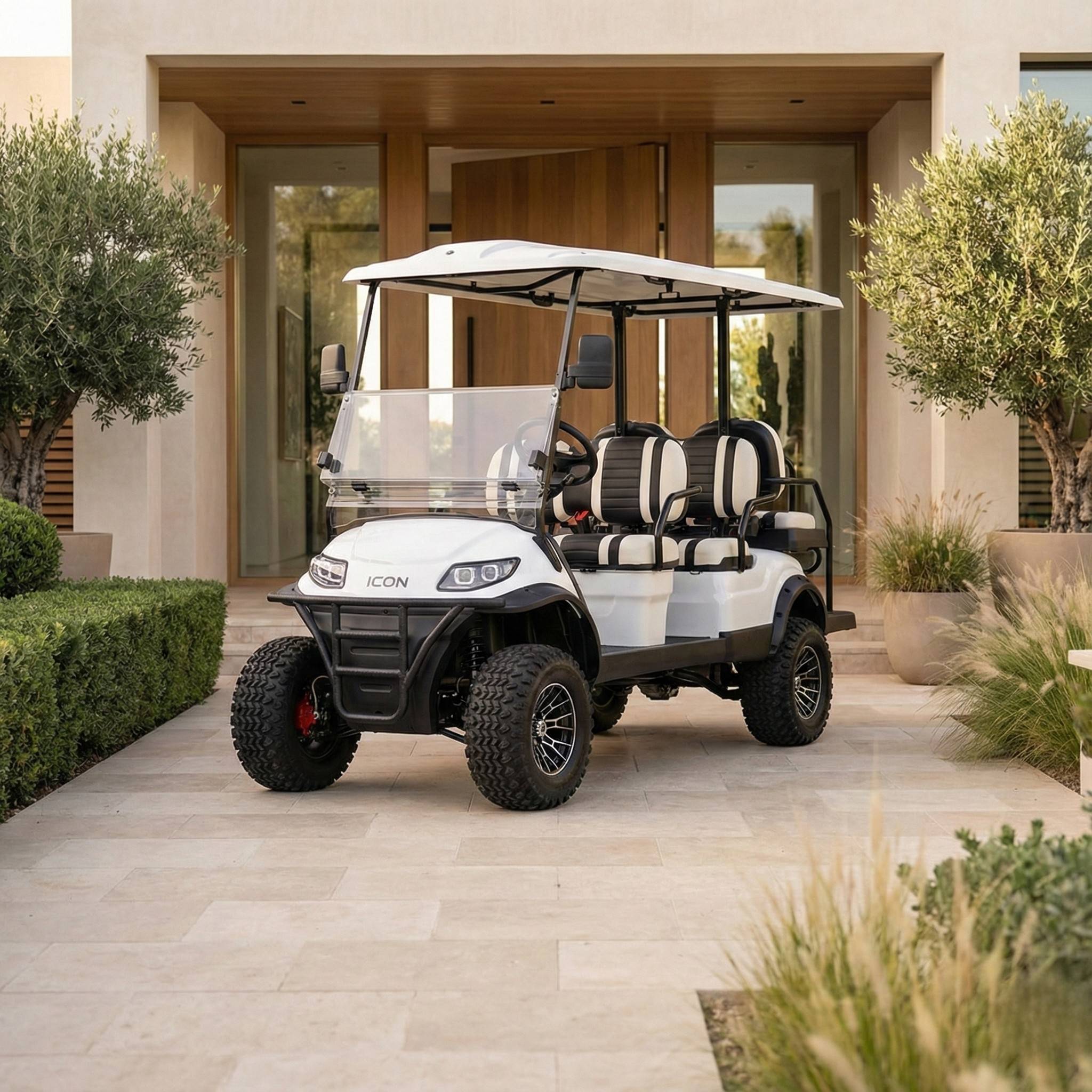 White golf cart with black seats parked on a stone pathway in front of a modern house.