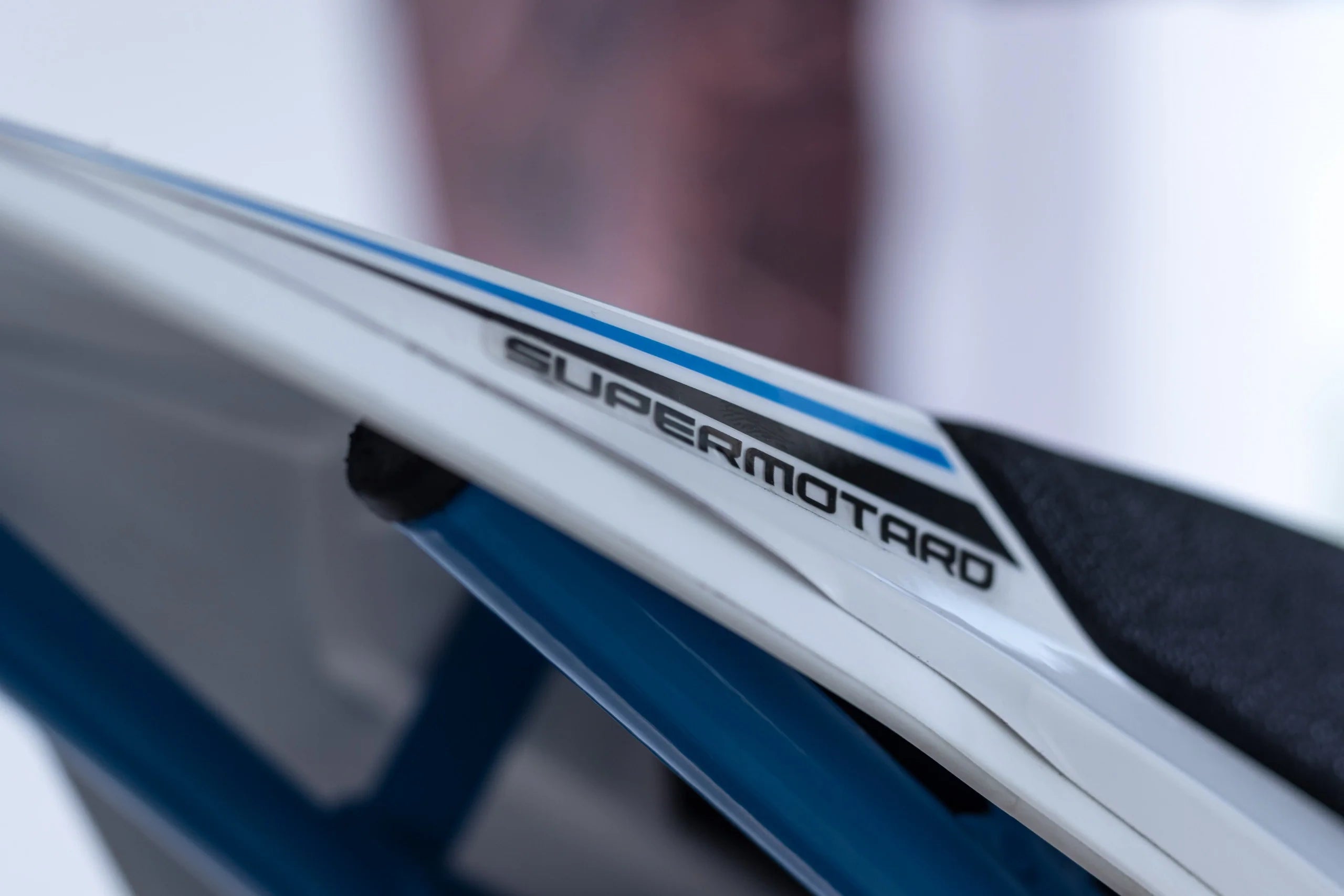 Close-up of a motorcycle with 'Supermoto' branding on a blurred background