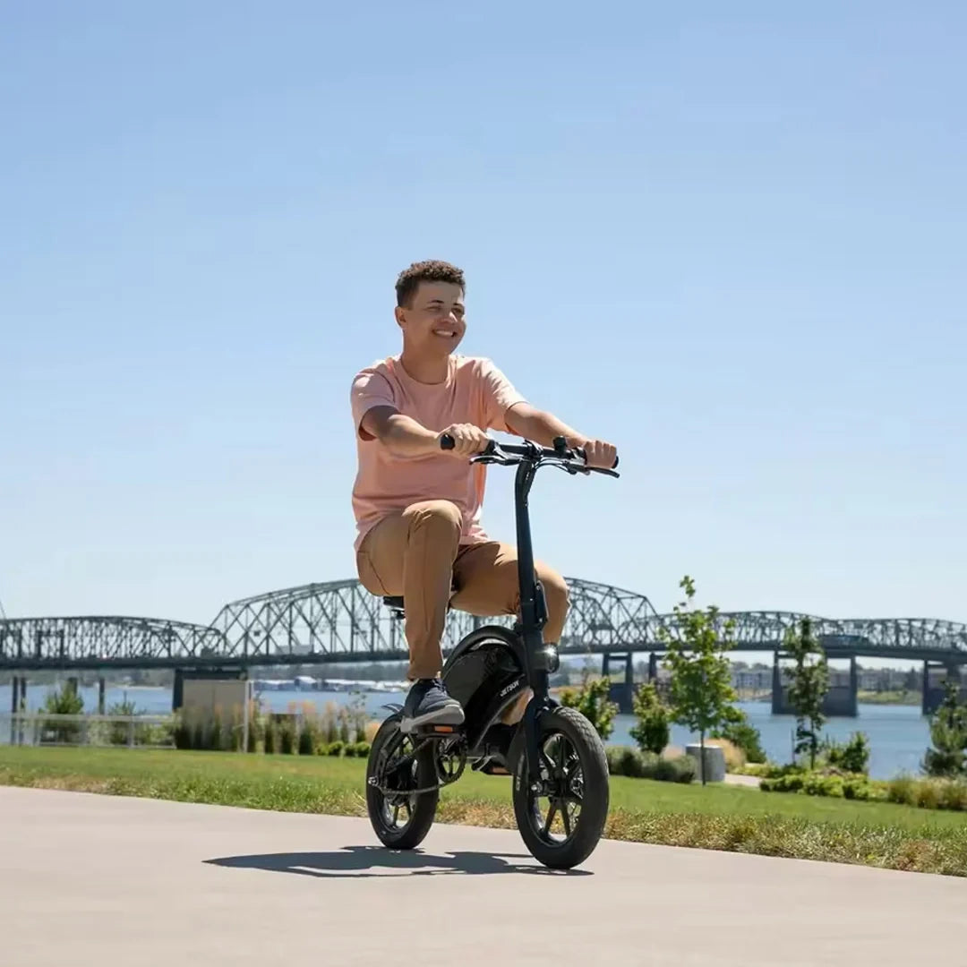 Person riding a scooter on a path with a bridge and water in the background