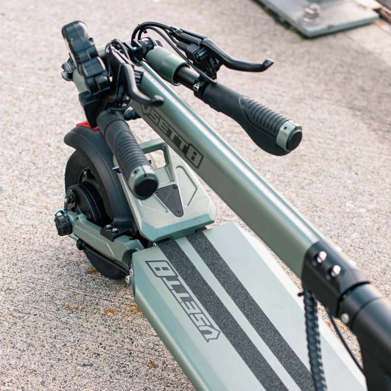 Close-up of a green electric scooter with visible branding on a concrete surface.