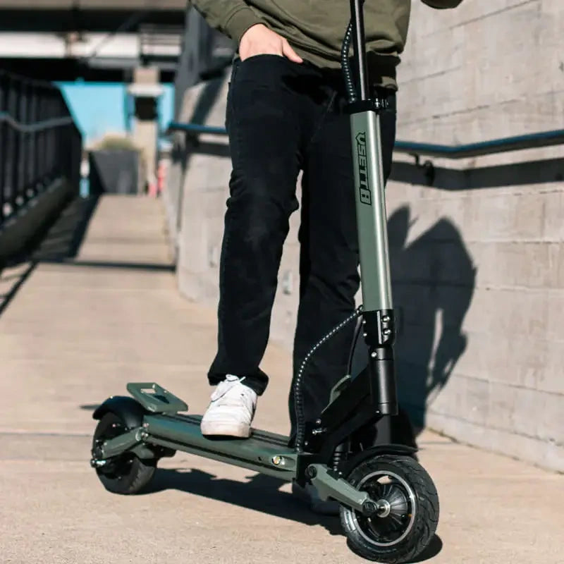 Person riding a black electric scooter on a sidewalk.