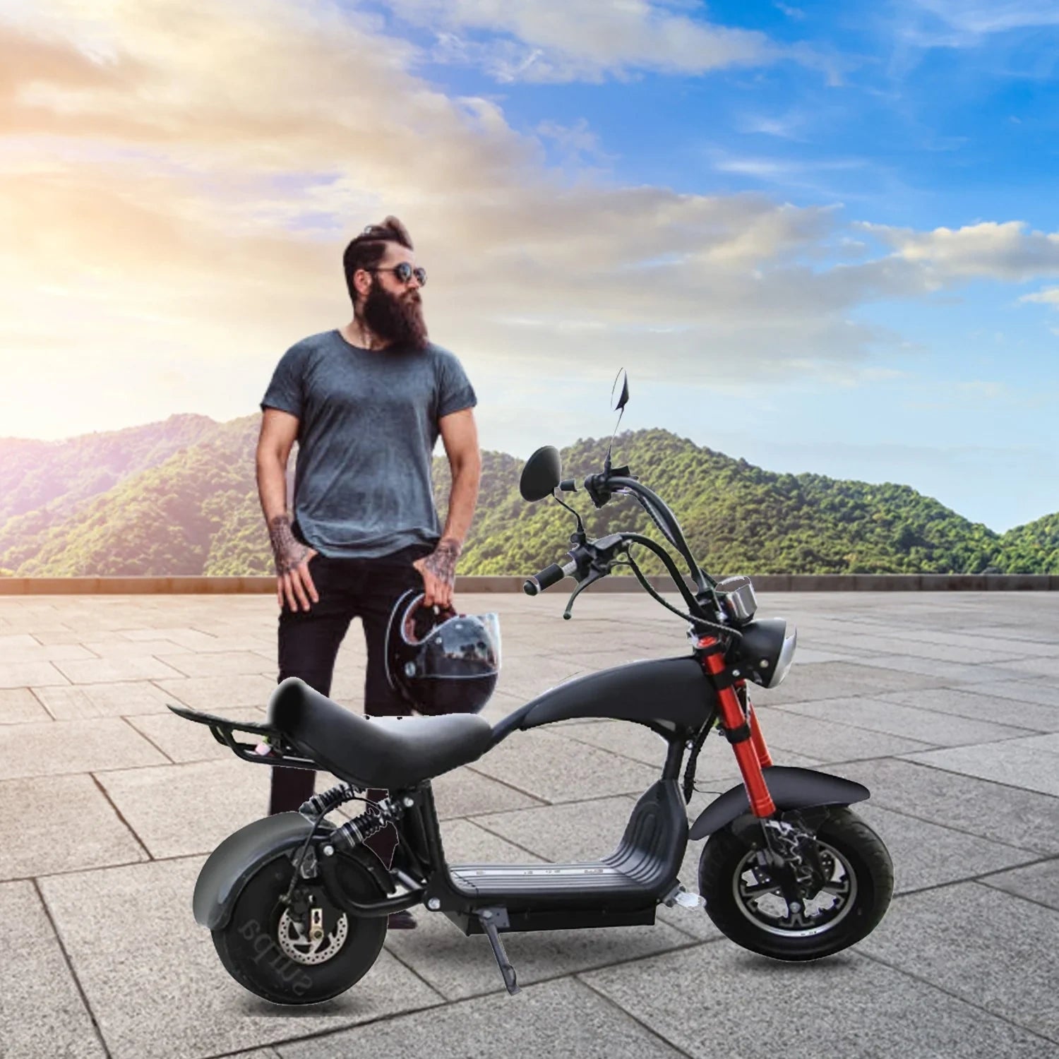 Man with a beard standing next to an electric scooter with a scenic background