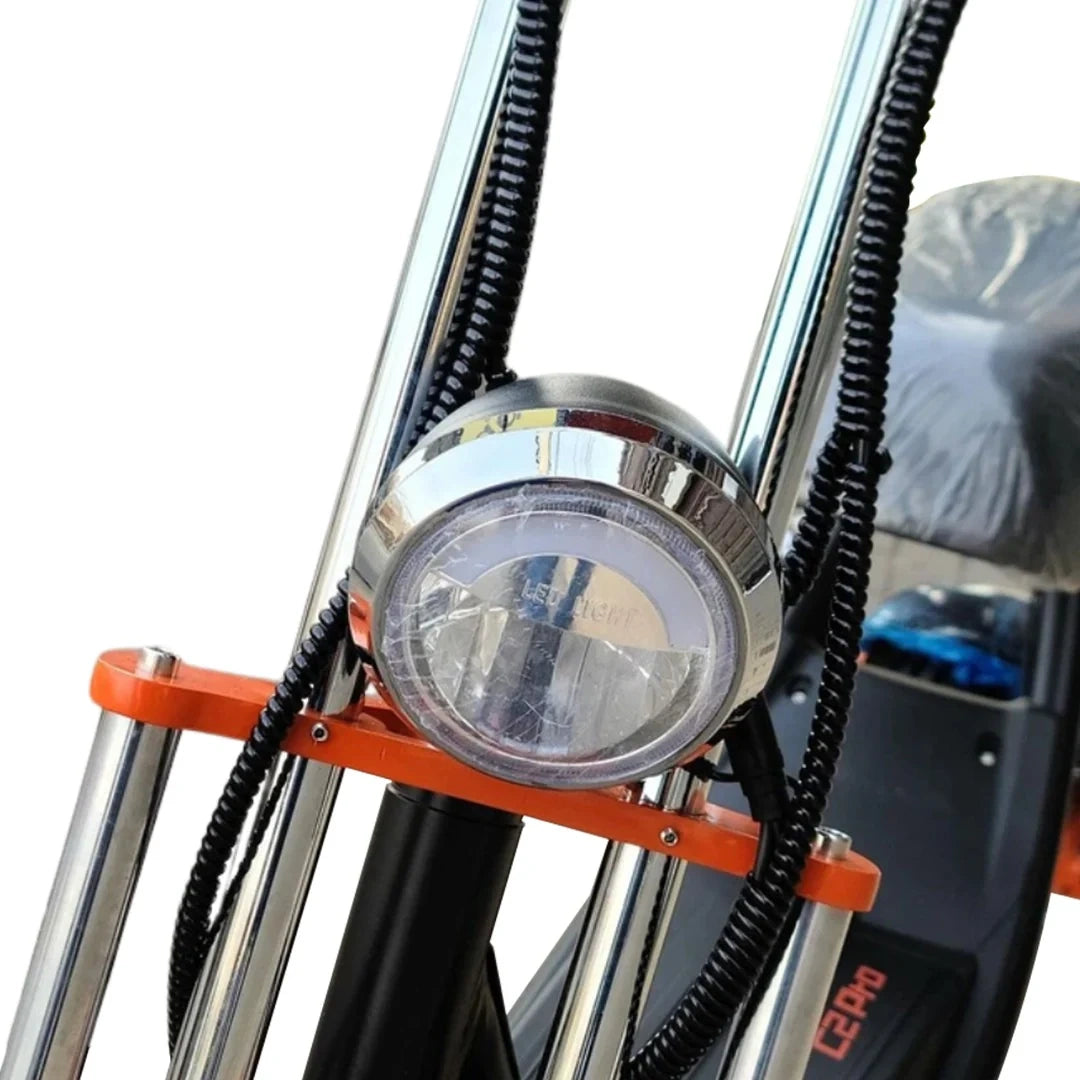 Close-up of a motorcycle headlight with orange accents on a white background