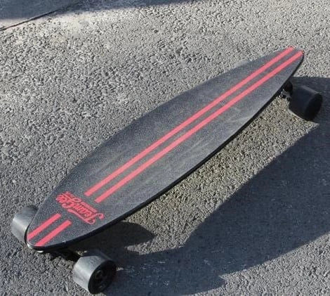 Black skateboard with red stripes on a concrete surface