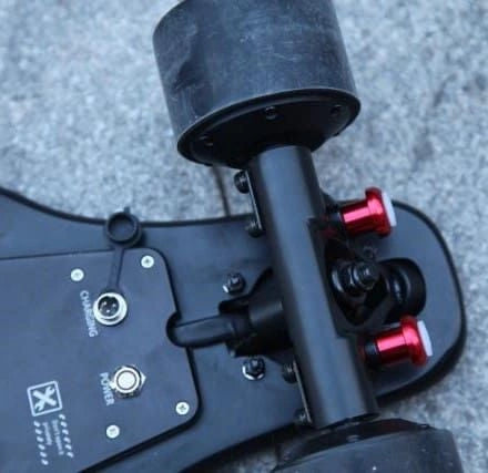 Close-up of a black electric skateboard with red hardware on a concrete surface