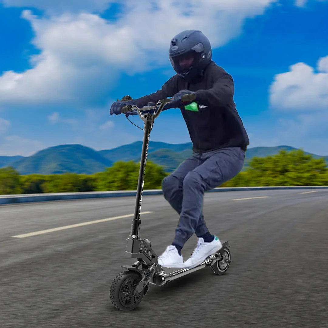 Person riding an electric scooter on a road with mountains in the background