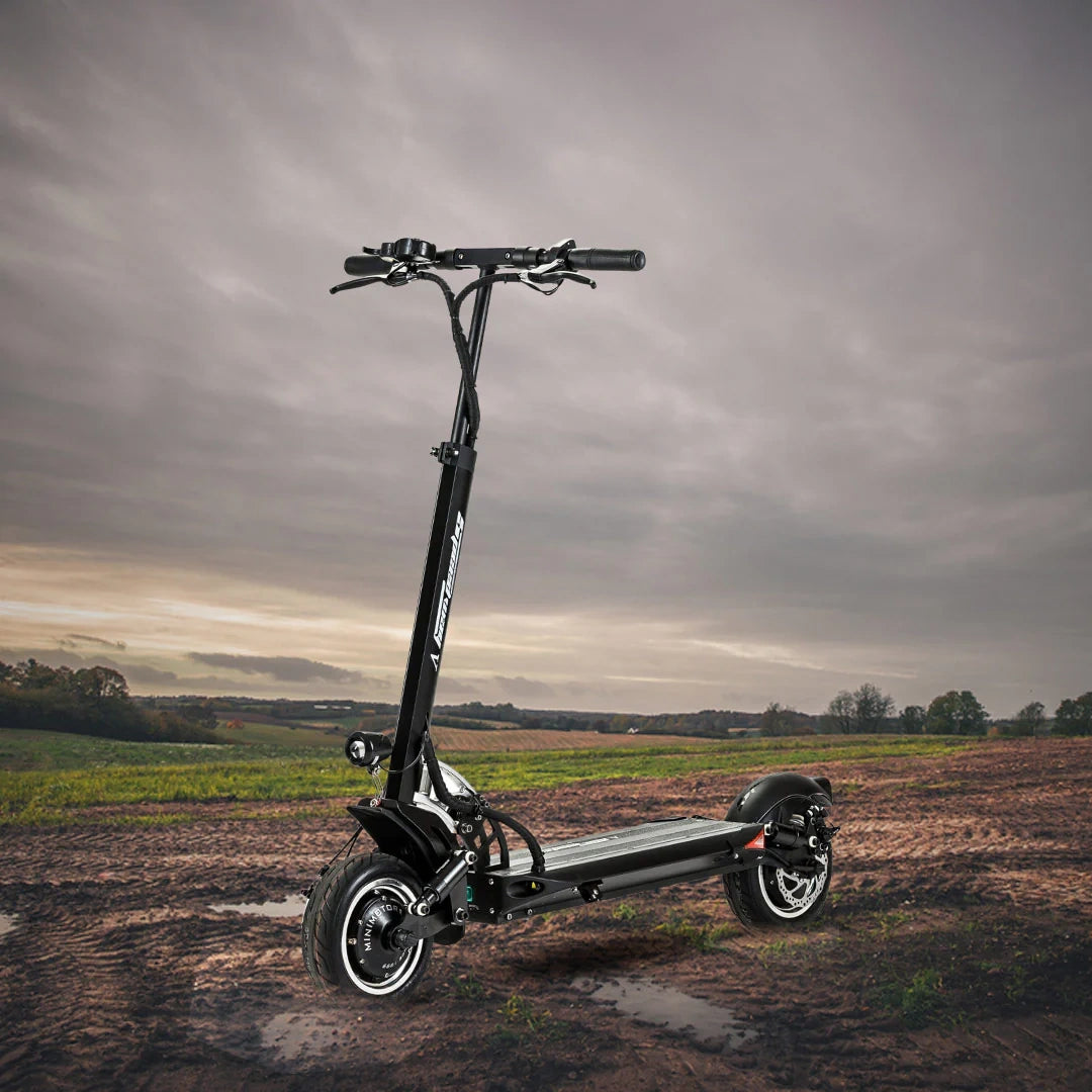 Black electric scooter on a field with a cloudy sky