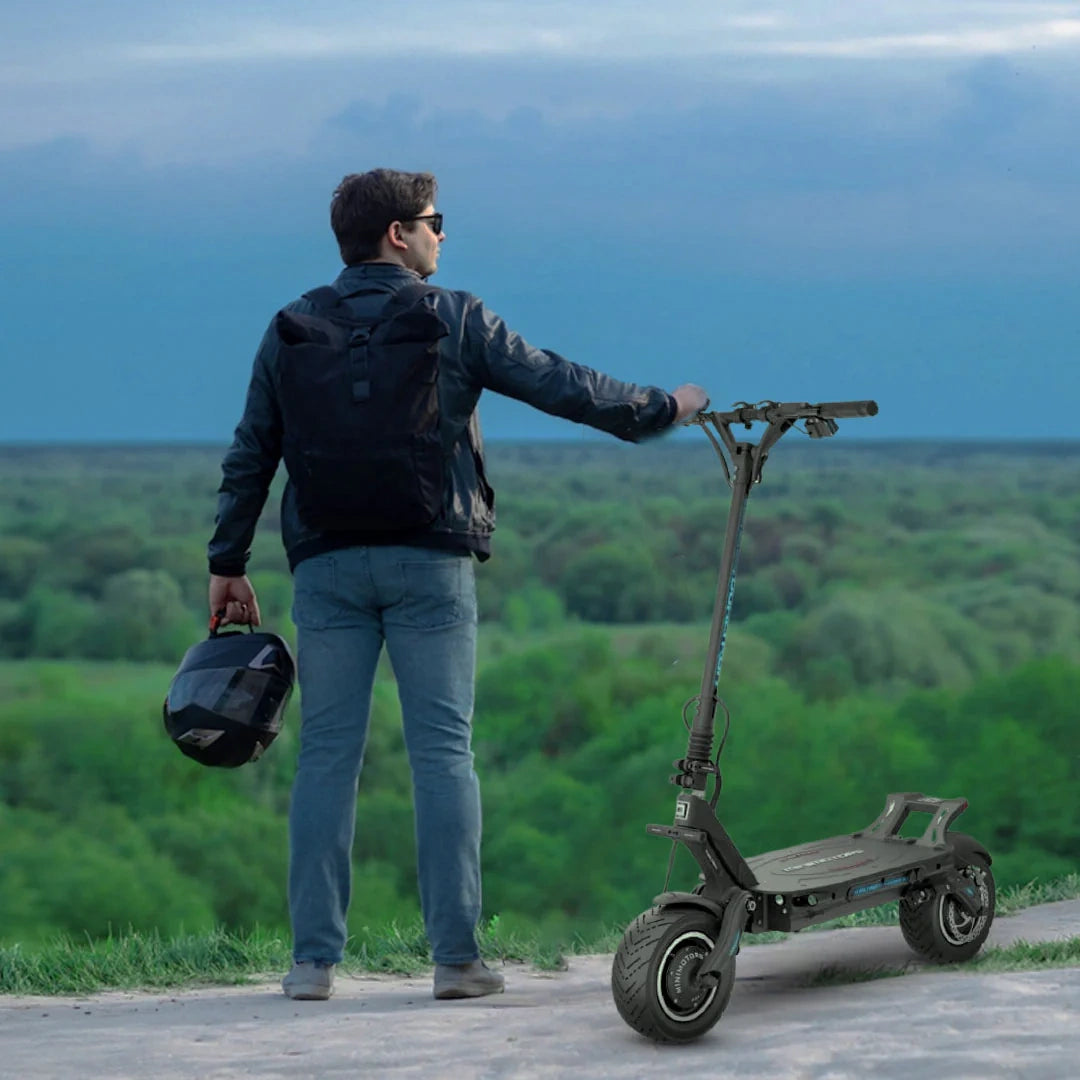 Man with electric scooter and helmet overlooking a scenic landscape