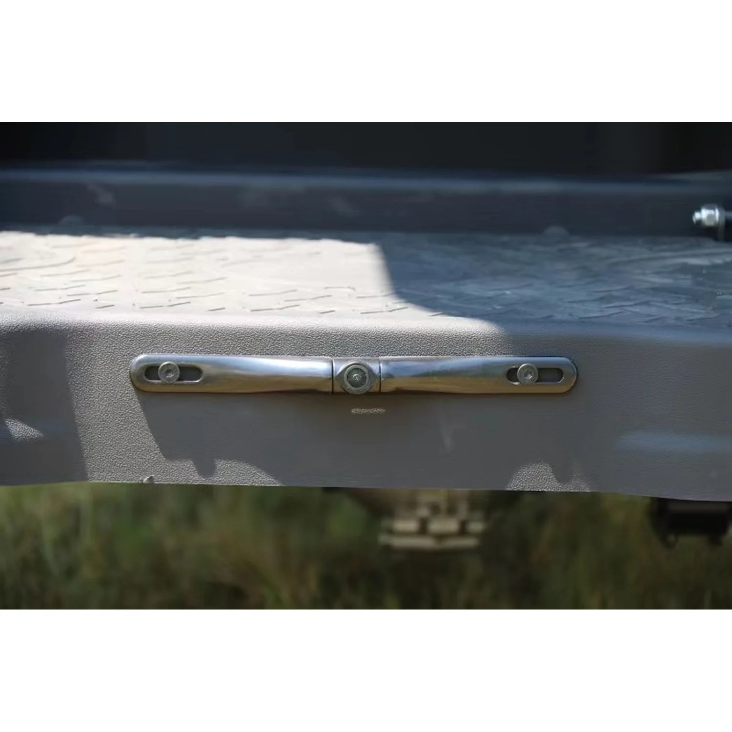 Metallic handle on a vehicle door with grass and pavement in the background