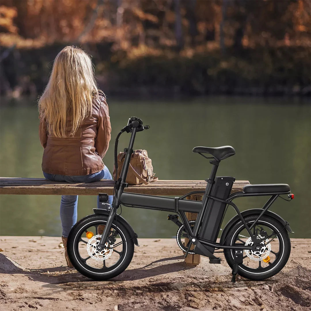 Person sitting on a bench with an electric bike by a body of water
