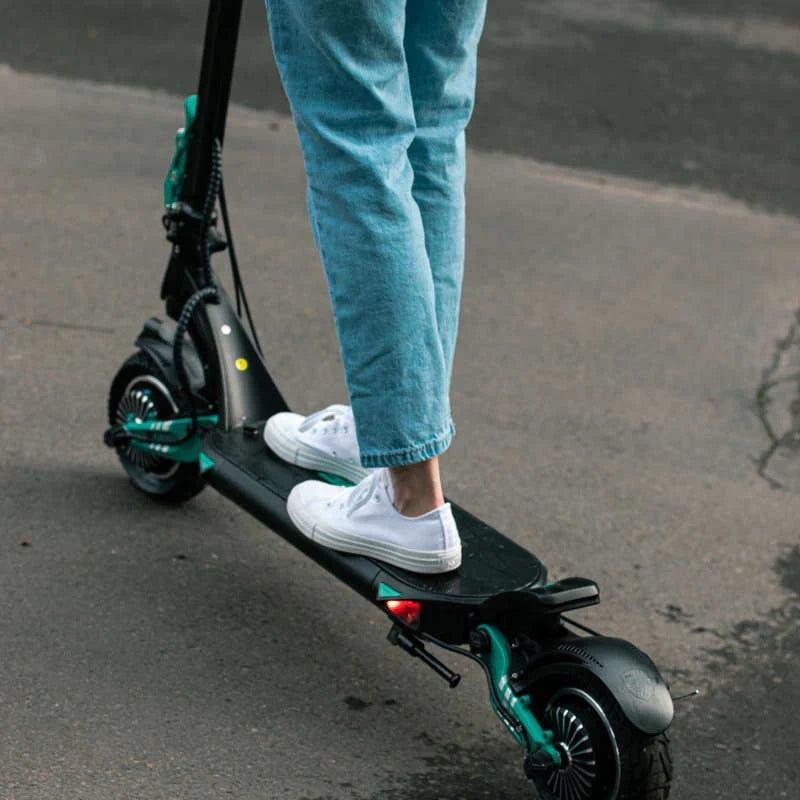 Person riding a black electric scooter on a road.