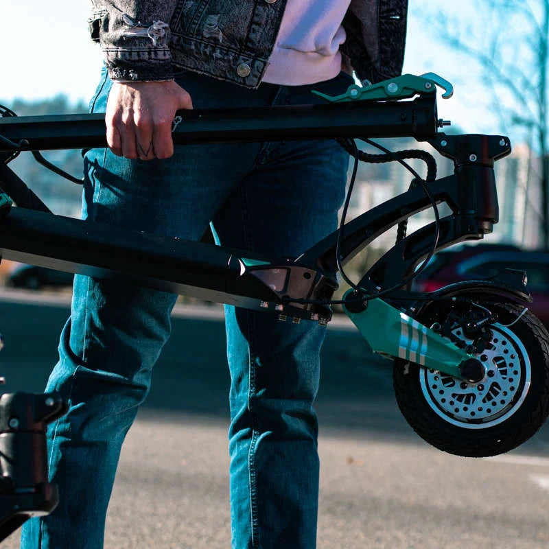 Person holding a folded electric scooter on a blurred background