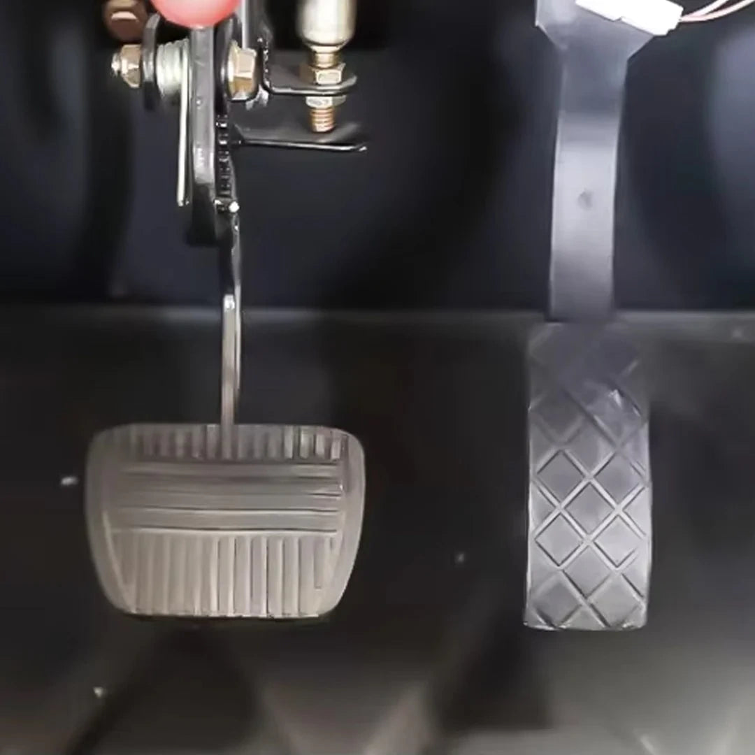 Close-up of car pedals with a hand on the brake pedal.