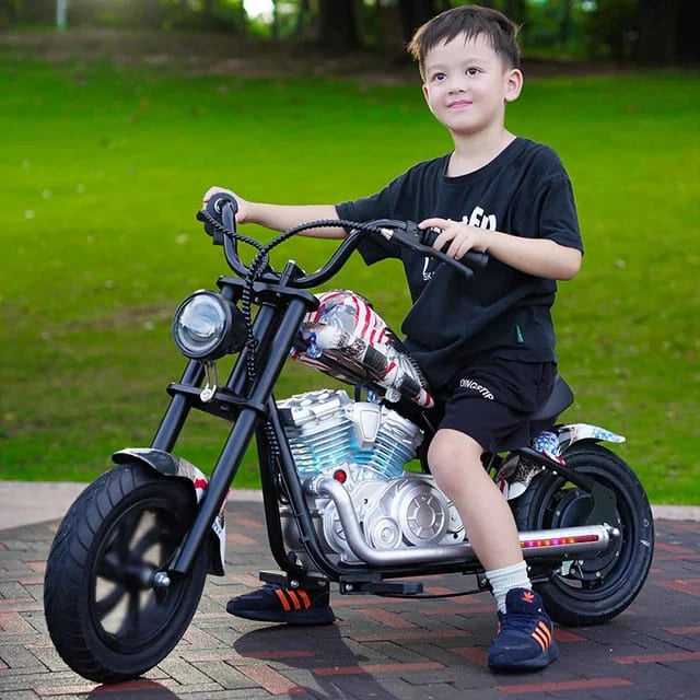 Child sitting on a toy motorcycle with a detailed engine in an outdoor setting