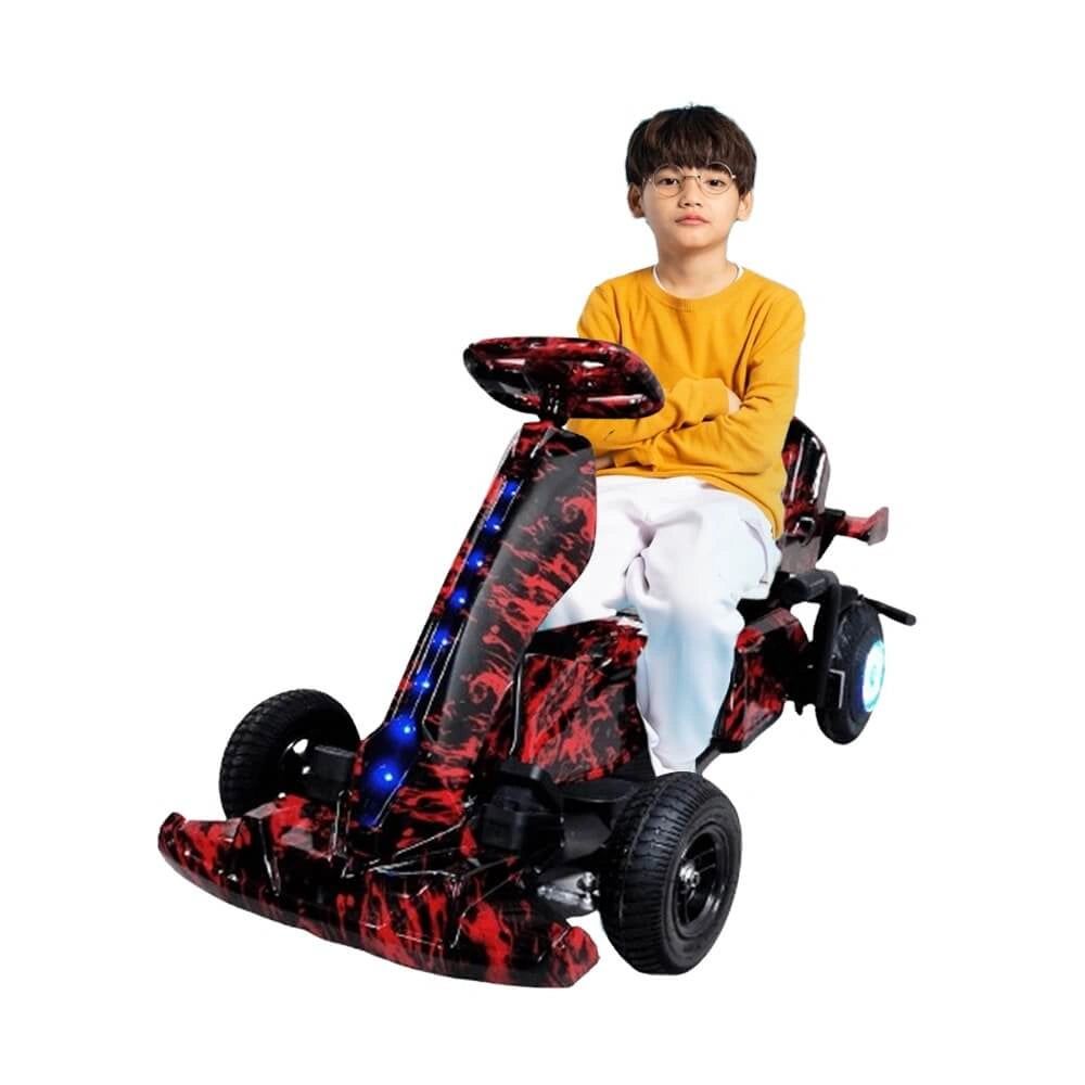 Child sitting on a red and black toy car with LED lights on a white background