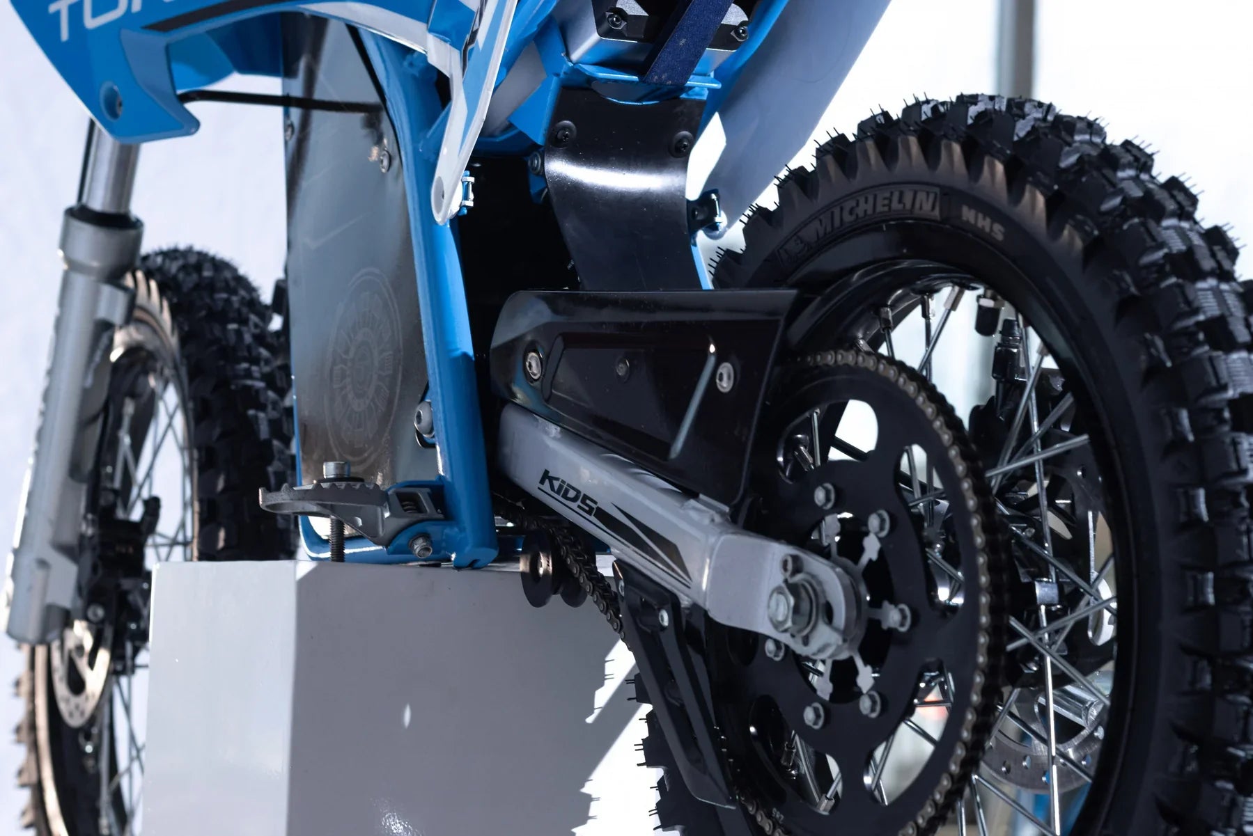Close-up of a blue dirt bike with visible branding on a white background